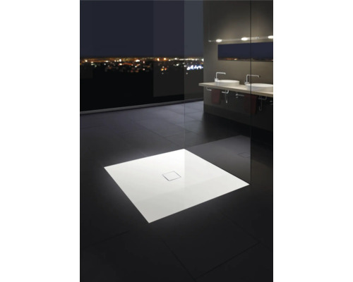 Elegante badkamer met vlakke douchebak, wastafels en raampartij met uitzicht op de stad bij nacht.