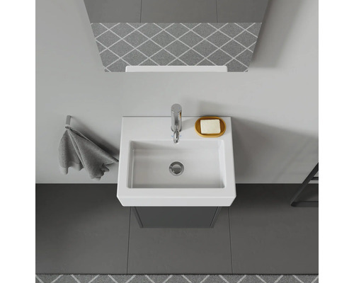 Topaanzicht van een badkamer met wastafel, kraan, zeepbakje en handdoekhouder