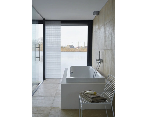 Badkamer met bad, douchewand en raam met uitzicht op het meer