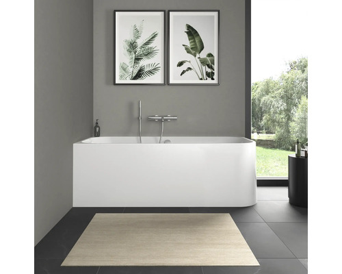 Badkamer met bad, kraan, vloerkleed en wanddecoraties