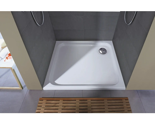 Vierkante douchebak van gegoten mineraal in een grijze douchecabine met houten rooster.