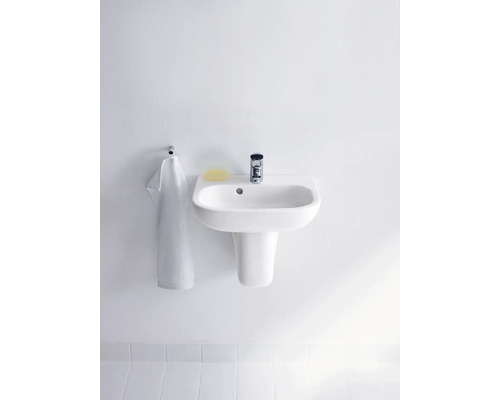 Wastafel met kraan, zeep en handdoek aan een muur gemonteerd