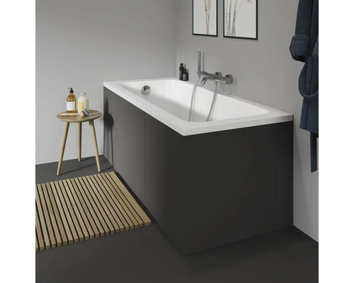 Badkamer met bad, kraan, houten badmat en kruk