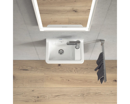 Bovenaanzicht van een badkamer met wastafel, spiegel en handdoekhouder.