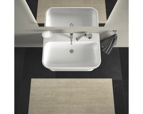 Bovenaanzicht van een badkamer met wastafel, spiegel, handdoek en badmat