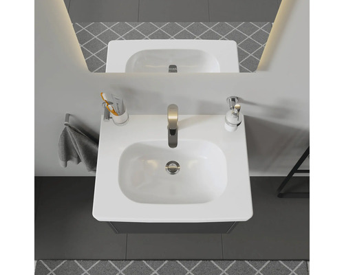 Bovenaanzicht van een badkamer met wastafel, kraan, handdoek en accessoires.