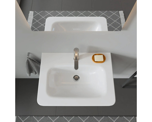 Bovenaanzicht van een wastafel met kraan, zeep en handdoek