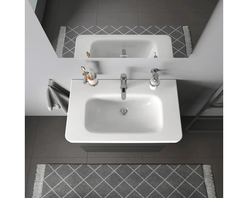 Bovenaanzicht van een wastafel in de badkamer met kraan, zeepdispenser, tandenborstelbeker en handdoek