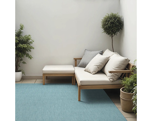 Terras met tapijt, tuinmeubelen en planten in potten.