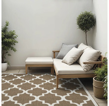 Tuinscene met loungesofa, voetenbank, sierkussens, planten en buitenkleed met patroon