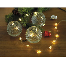 Decoratie met sterrenlichtsnoer, waxinelichtjes en kerstboomtak op houten tafel