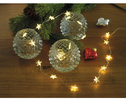 Decoratie met sterrenlichtsnoer, waxinelichtjes en kerstboomtak op houten tafel