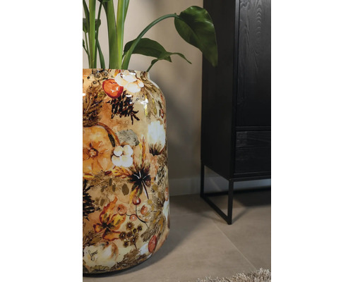 Decoratieve bloemenvaas met plantenmotief naast een zwarte kast