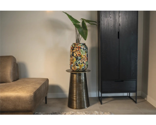Decoratieve plant in vaas met bloemmotief op een bronskleurige tafel naast een zwarte kast