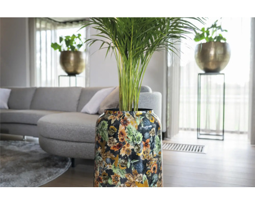 Woonkamer met plant in pot met bloemmotief, grijze bank en decoratieve bloempot op een standaard