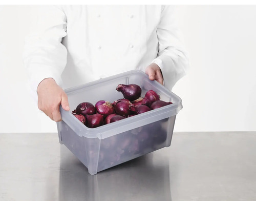 Een persoon in een koksbuis houdt een grijze kunststof box gevuld met rode uien vast.