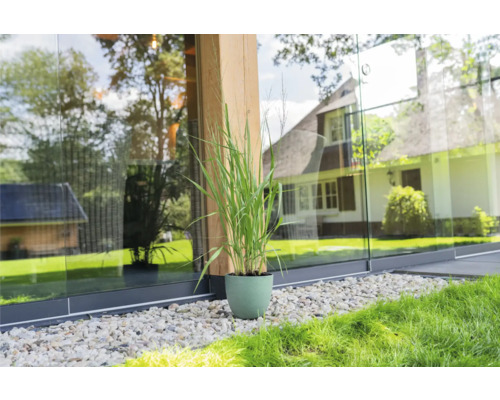 Siergras in een pot op grind naast een glazen schuifpui