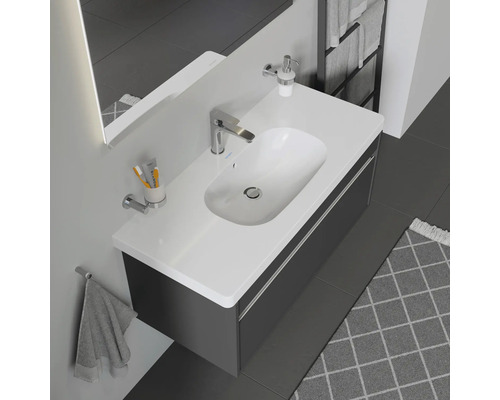 Moderne badkamer met wastafel, onderkast, kraan, zeepdispenser, handdoek en andere badkameraccessoires.