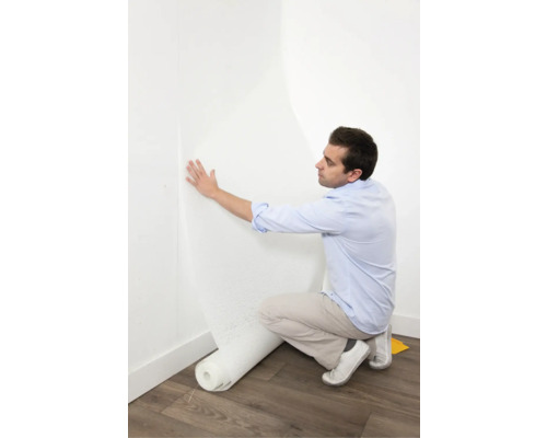 Een man brengt een glasvezelbehang aan op een muur.