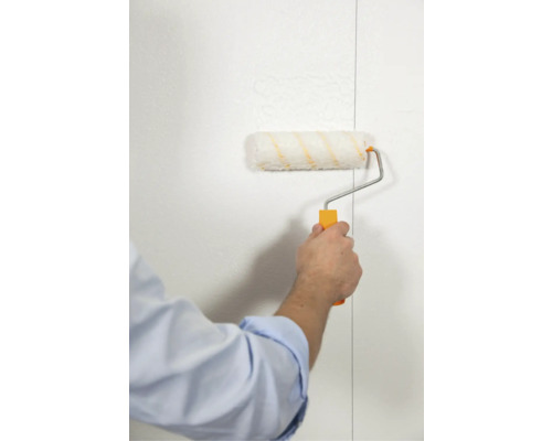Een persoon schildert een muur met een verfroller. De verfroller is bedekt met verf.