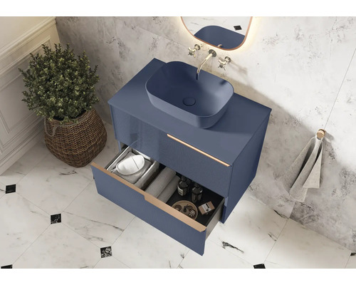 Moderne badkamer met blauwe wastafelonderkast, opzetwastafel en open lade voor het opbergen van badkamerbenodigdheden.
