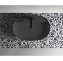 Bovenaanzicht van een ovale, zwarte opzetwastafel met kraan op een werkblad met terrazzo-patroon.