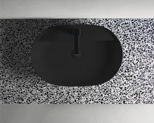 Bovenaanzicht van een zwarte opzetwastafel op een oppervlak met patroon