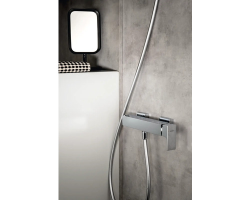 Foto van een badkamer met een douchearmatuur, een spiegel en een opbergruimte