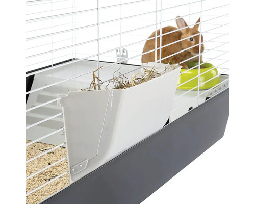 Detailopname van een konijnenkooi met hooiruif en voerbak