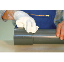 Hand met doek reinigt grijze PVC buis.