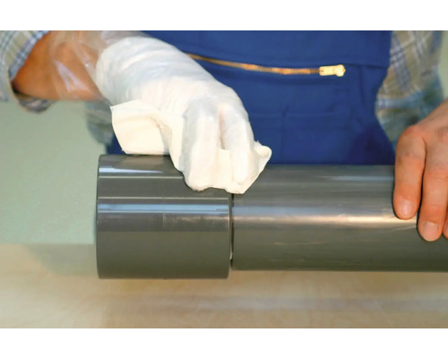 Hand met doek reinigt grijze PVC buis.