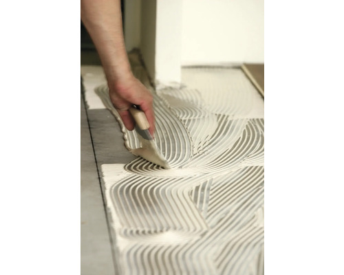 Tegellijm aanbrengen met een lijmkam voor het plaatsen van tegels