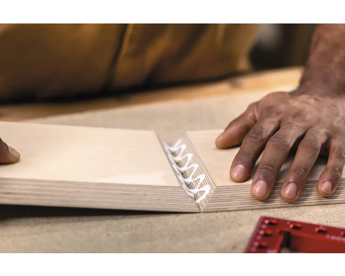 Een persoon lijmt twee houten platen aan elkaar.