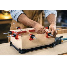 Man fixeert houten kist met randklemmen en spanband