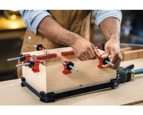 Man fixeert houten kist met randklemmen en spanband