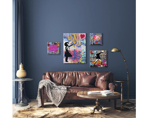 Woonkamer met leren bank, salontafel, staande lamp en vier muurschilderingen in graffitistijl