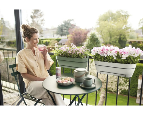 Vrouw zit op balkon met balkonbakken, tafel en drankjes