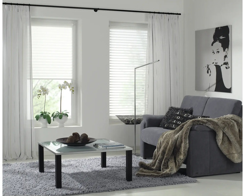 Lichte woonkamer met bank, salontafel, raamdecoratie en kunst