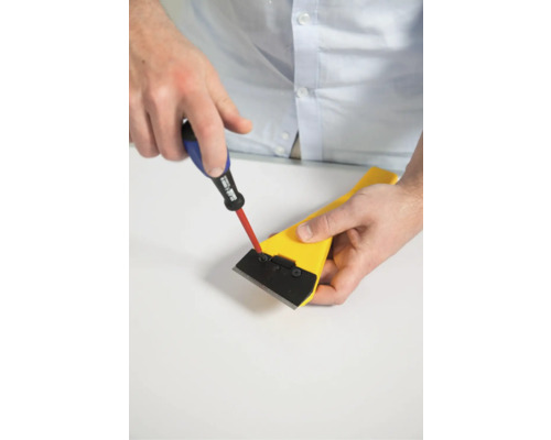 Iemand bevestigt het mes van een schraper met een schroevendraaier.