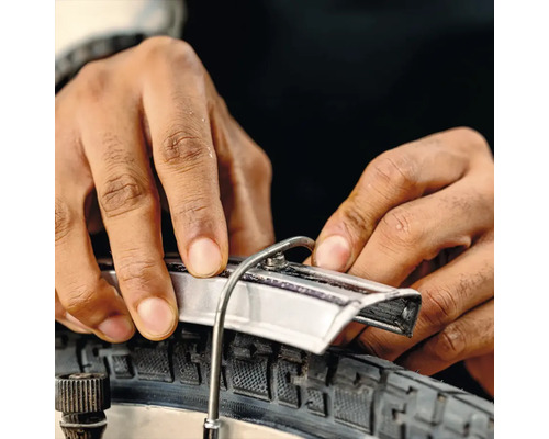 Close-up van een persoon die een fietsband met een bandenlichter monteert.