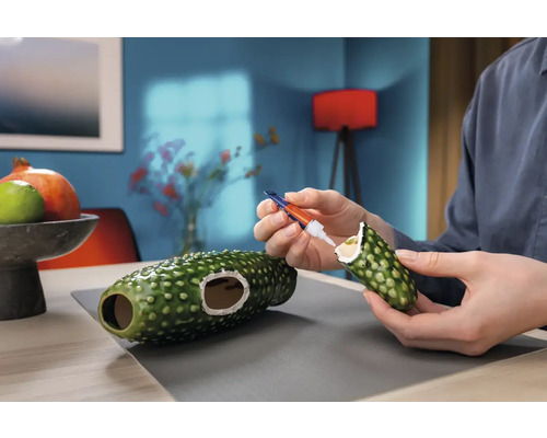 Persoon repareert een decoratief object met lijm.