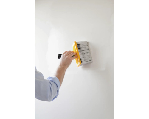 Iemand gebruikt een blokkwast om verf op een muur aan te brengen.