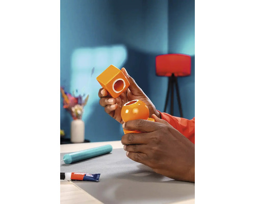 Twee oranje keramische vormen worden samengevoegd, een lijm ligt op tafel.