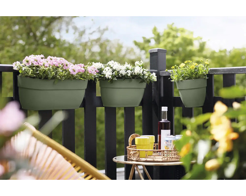 Balkonscène met bloembakken aan een reling, beplant met roze, witte en gele bloemen, met een tafel en stoelen op de voorgrond