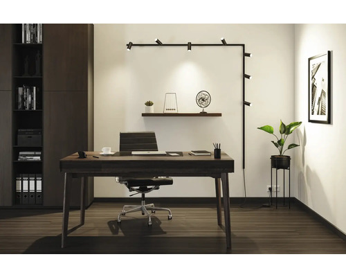 Moderne werkkamer met bureau, bureaustoel, rekkensysteem en wandlamp.
