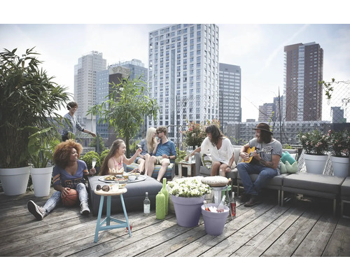 Scene op een dakterras met mensen, planten in potten en modulaire loungemeubels.