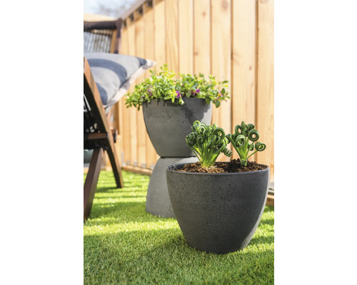 Twee beplante kunststof bloempotten op gazon