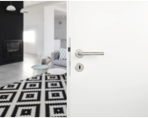 Open witte deur met roestvrijstalen handgreep naar een woonkamer met tapijt