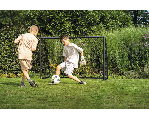 Twee jongens spelen voetbal voor een voetbaldoel in de tuin.
