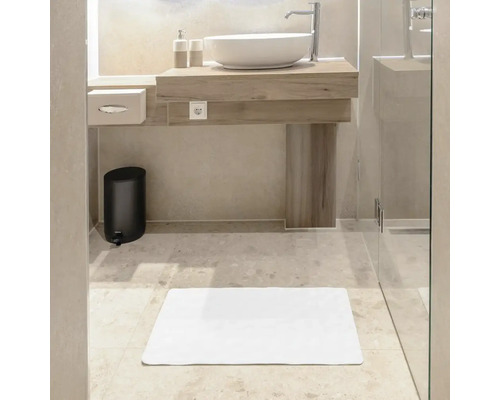 Badkamer met wastafel, spiegel, afvalemmer en badmat